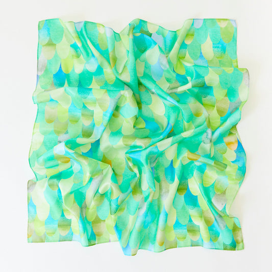 A crumpled square Playsilk, crafted from natural materials, features a green and blue scallop pattern on a white background—perfect for open-ended toys and imaginative play.